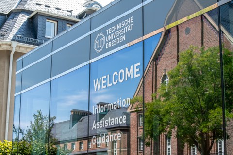 Foto einer verspiegelten Fassade mit dem Logo der TU Dresden und der Aufschrift "Welcome".