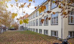  Das Foto zeigt den Günther-Landgraf-Bau der TU Dresden. Die Wiese vor dem Gebäude ist mit Laub bedeckt. 